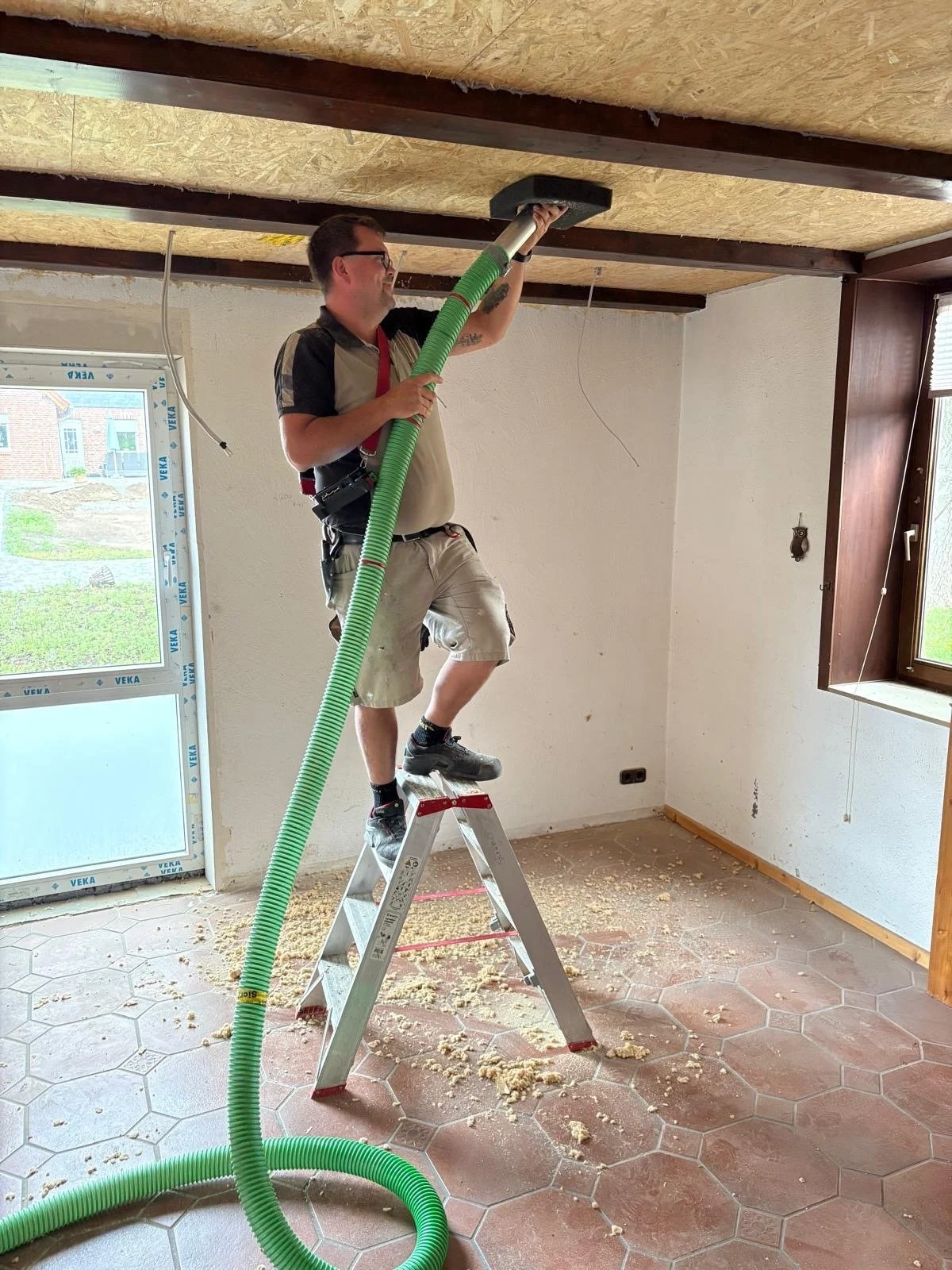 Einbringen von Dämmstoff mit einem Schlauch in einen Deckenhohlraum